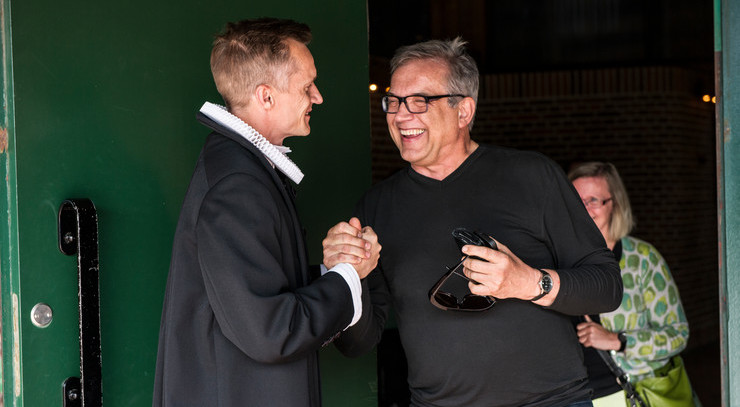 Præst trykker hånd med grinende kirkegænger